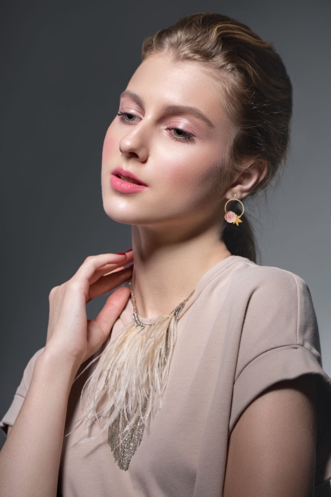 Beauty fashion portrait of a young beautiful girl posing in the Studio. Bright evening makeup, stylish clothes. Hand touches decoration